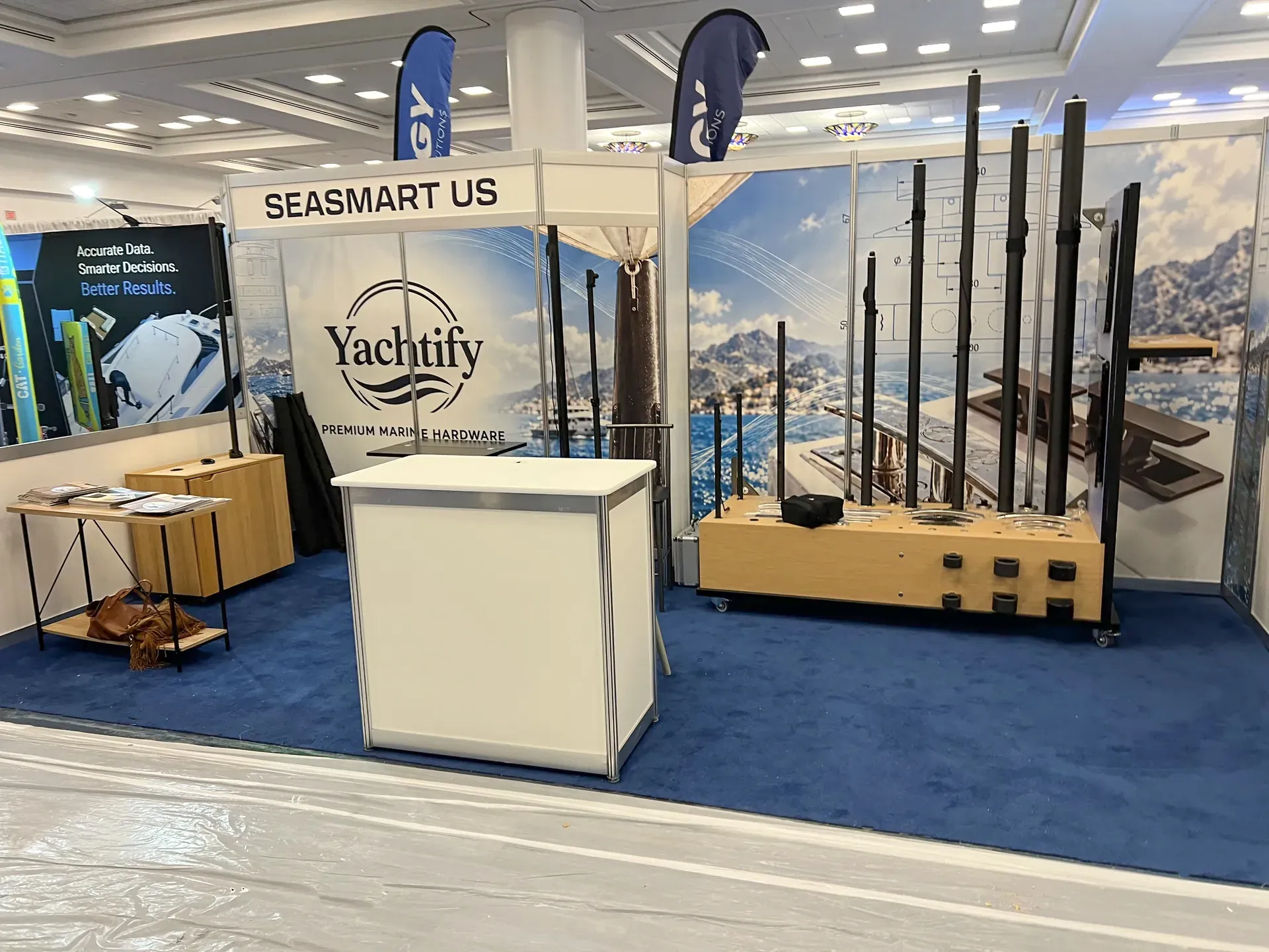 Yachtify’s IBEX stand with a reception counter, marine hardware display and yacht photography backdrop.