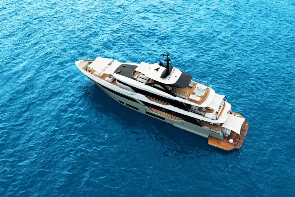 Aerial view of a white motor yacht on bright blue water.