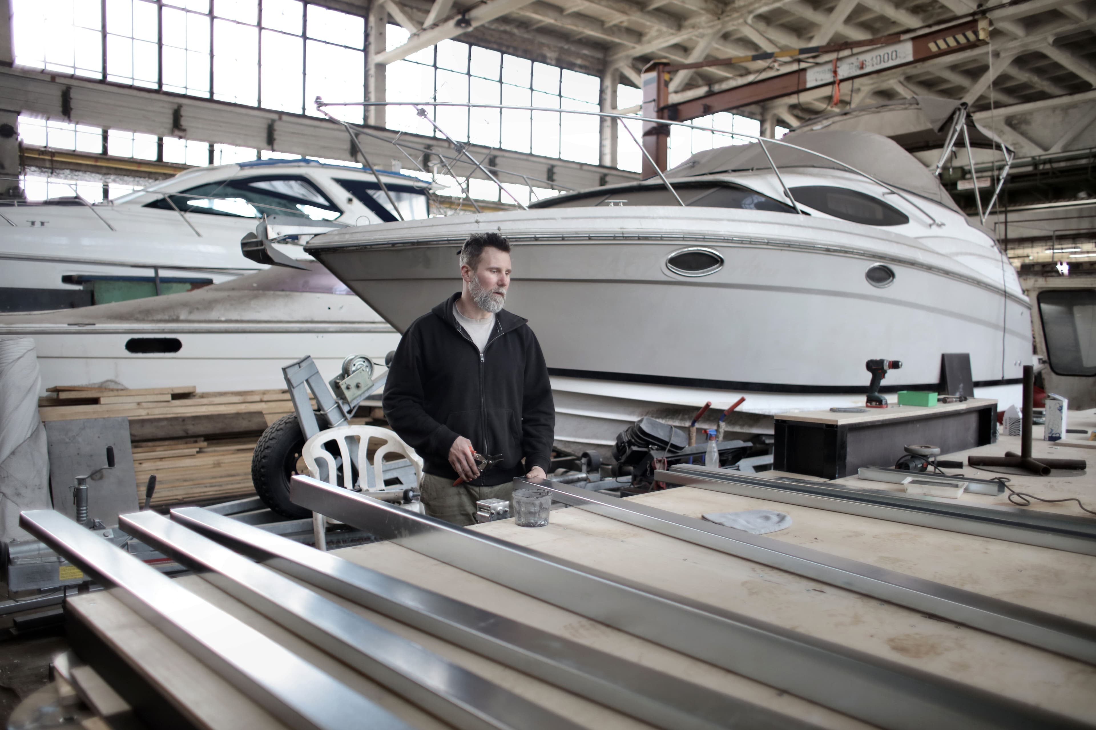 Marine workshop professional preparing metal components beside yachts